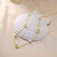 Clover and Pearl Station Necklace showcasing gold and pearl design on a soft shell background.