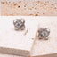 Moissanite Knot Stud Earrings ā Sterling Silver (8mm) on a textured surface with a blurred background