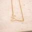 Gold necklace with 'Ella' pendant on a beige surface. Personalised Name Necklace – 18K Gold-Plated
Waterproof | Hypoallergenic | Made-to-Order