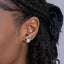 Close-up of an ear with a Moissanite Knot Stud Earrings ā Sterling Silver (8mm), model hair styled in braids.