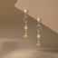 Gold earrings with moon, star, with blue gemstone designs on a brown background