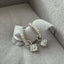 Silver earring with clear gemstones on a gray surface