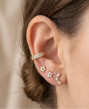 Close-up of an ear wearing gold and diamond earrings with a blurred background