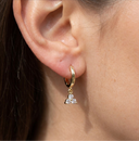 Gold earring with a small diamond on an ear against a neutral background