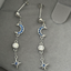 Silver earrings with moon and star designs on a grey surface