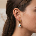 Close-up of an ear wearing a gold hoop earring with colorful beads.