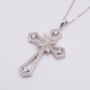 Radiant Cross Necklace – Sterling Silver | Rhodium-Plated. A silver cross pendant necklace adorned with small clear stones, featuring a central floral motif and a delicate chain, set against a plain light background.