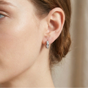 Close-up of a person wearing a silver hoop earring with a neutral background