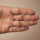 Zodiac Constellation CZ Flat Back Earring – 16G Push Pin Cartilage Stud- A hand holding multiple silver-toned constellations stud earrings, each connected by a thin bar and set with small clear stones, against a plain beige background.