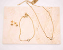 Mini CZ Bracelet and matching gold stud earrings on a textured stone surface.