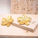 Close-up of sculpted gold floral earrings showing petal detail