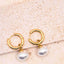 Gold hoop earrings with pearl drops on a beige surface