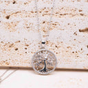 Tree of Life Necklace – Rhodium-Plated Silver showcased on a textured surface with intricate tree design.