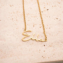 Gold necklace with 'Ella' pendant on a beige surface. Personalised Name Necklace – 18K Gold-Plated

Waterproof | Hypoallergenic | Made-to-Order
