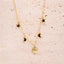 Gold necklace with star, moon, and sun pendants on a textured beige background. Ella and Faith London