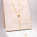 Moissanite Drop Pendant Necklace displayed on a textured stone background, featuring an elegant golden chain design.