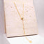 Gold plated sterling silver moissanite drop sweater necklace displayed on a natural stone background