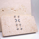 Pair of silver earrings with blue gemstones on a textured beige surface