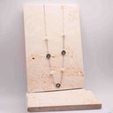 Clover and Pearl Station Necklace – Gold or Silver. Necklace with pearls and a clover flower on a beige stone stand against a light grey background.