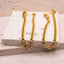 Gold chain earrings on a textured white surface