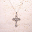 Silver cross necklace on a textured beige surface