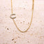 Gold necklace with a Horseshoe pendant on a textured beige surface
