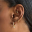 Close-up of an ear with gold huggie hoop earrings