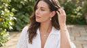 Woman in a white outfit outdoors with greenery in the background wearing Ella & Faith London Jewellery