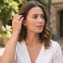 Woman wearing gold jewelry outdoors with a blurred background
