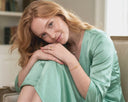 Woman in a light green dress sitting on a couch in a home setting wearing Ella and Faith London Jewellery