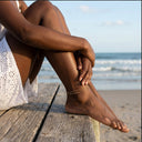 Person sitting on a wooden bench at the beach with legs crossed wearing Ella and Faith London Anklet