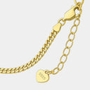 Gold chain bracelet with a heart-shaped tag on a light gray background