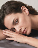 Close-up of a woman with her hand on her face, wearing a gold earring.