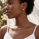 Woman wearing gold hoop earrings and necklaces outdoors