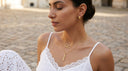 Woman wearing gold necklaces and earrings outdoors on a stone path