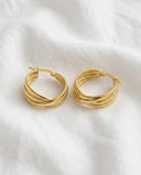 Gold hoop earrings on a white fabric background