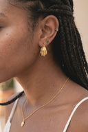 Close-up of a person wearing gold earrings and necklace with a blurred background