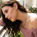 Woman wearing a pink off-shoulder top with a blurred outdoor background