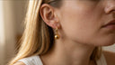 Close-up of a person wearing a gold earring with a blurred background
