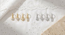 Mini Clicker Hoop Earrings 16G – Gold CZ Rook Cartilage & Tragus Piercing, on white broiderie Anglaise fabric.