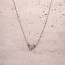 Silver heart-shaped pendant necklace on a textured beige surface