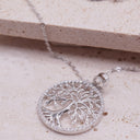 Silver tree of life pendant on a beige stone surface