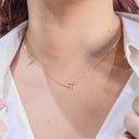 Gold necklace with a heart-shaped clasp worn by a person