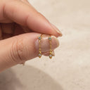 Dainty CZ Drop Chain Stud Earrings- Gold chain earrings held between fingers against a neutral background