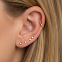 Close-up of an ear with multiple gold Surgical Steel Clicker Hoop – Waterproof & Hypoallergenicon a neutral background