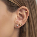 Close-up of an ear wearing gold star-shaped earrings with clear gemstones.