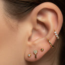 Close-up of an ear wearing gold earrings with gemstones.
