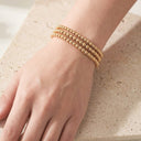 Gold Beaded bracelet on a wrist with a neutral background