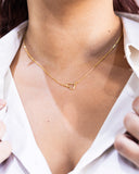 Gold necklace with a heart pendant worn by a person in a white shirt.