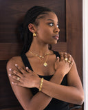 Woman wearing gold jewelry against a wooden background